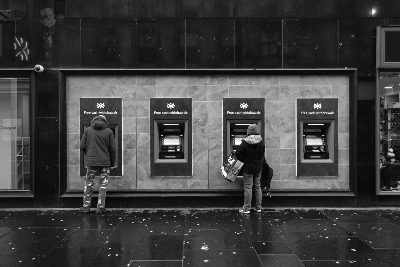 Two people using street-side ATMs