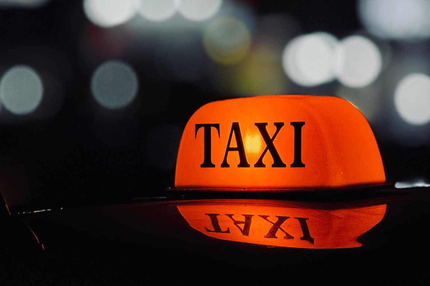 Glowing orange TAXI roof sign on a car at night in Korea