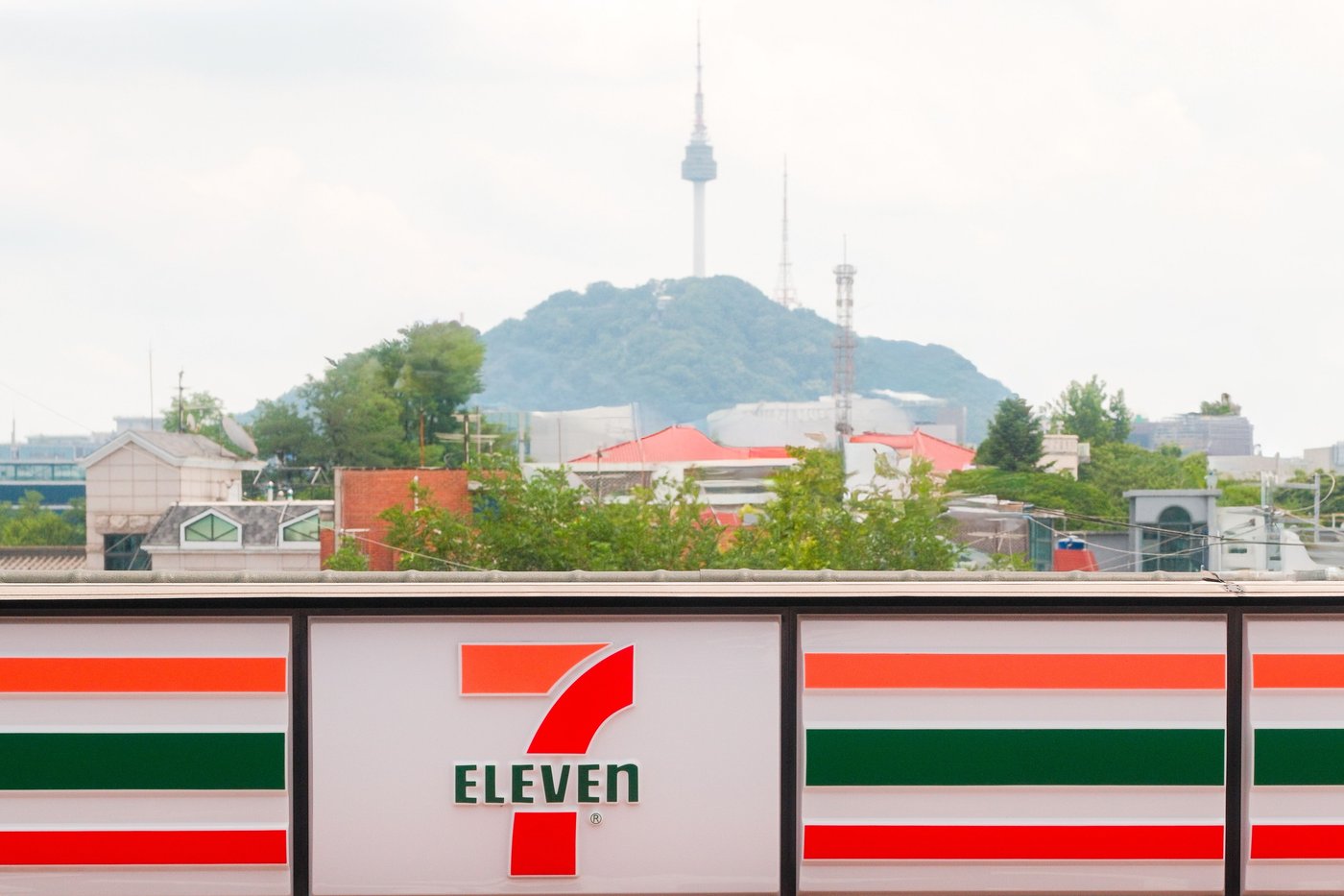 7-Eleven convenience store sign in Seoul with N Seoul Tower behind