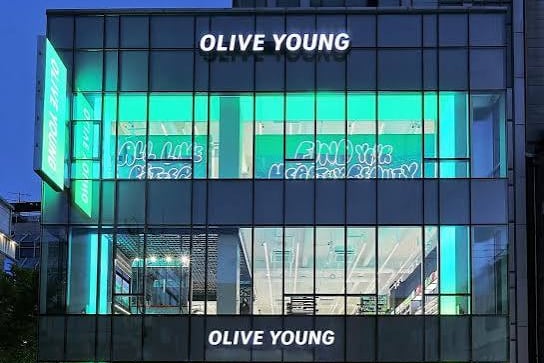 Olive Young flagship store at dusk with illuminated signage and glass facade