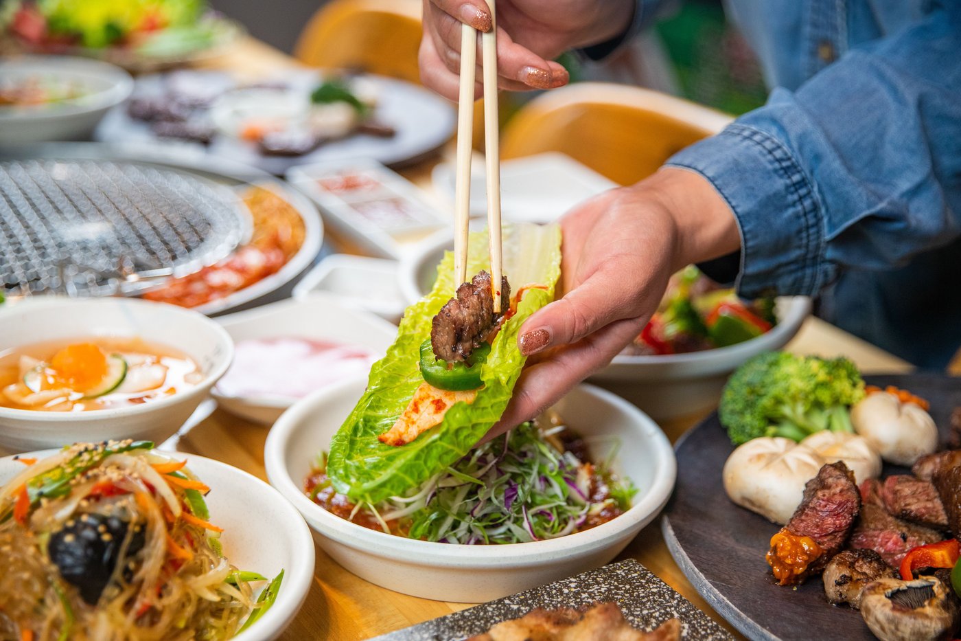 Placing grilled beef and kimchi onto a cabbage leaf with chopsticks